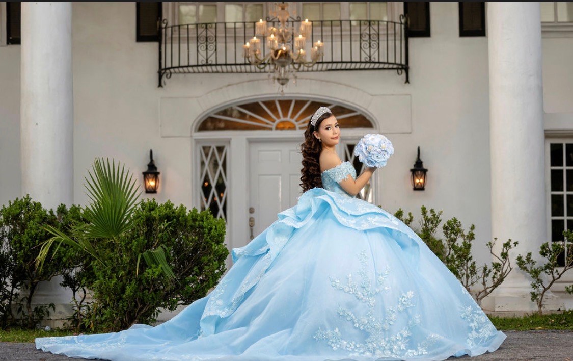 Carolina holding a blue and white bouquet in her ball gown